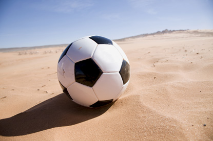 Ein schwarz, weißer Fußball liegt auf einem Sandplatz