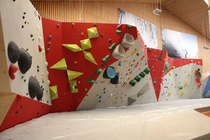 Eine Boulderwand mit leichten Überhängen und verschiedenen Steigungen ist mit farbenfrohen Griffen bestückt.