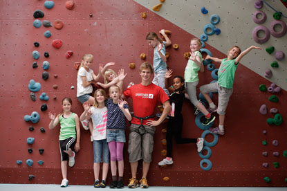 Einige Kinder vor einer Kletterwand und ein Trainer mit Sportpark Kelkheim Shirt grüßen die Kamera